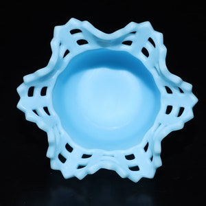 May include: A light blue glass bowl with a scalloped edge and a lace-like design. The bowl is empty and has a smooth, glossy finish.