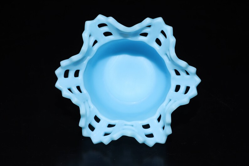 May include: A light blue glass bowl with a scalloped edge and a lace-like design. The bowl is empty and has a smooth, glossy finish.