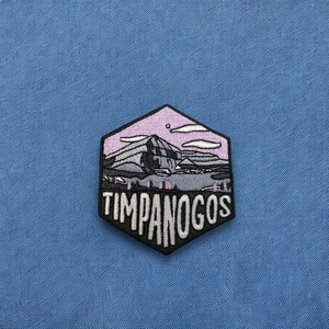 May include: A hexagonal embroidered patch with a pink and gray mountain scene and the text "TIMPANOGOS" in white.