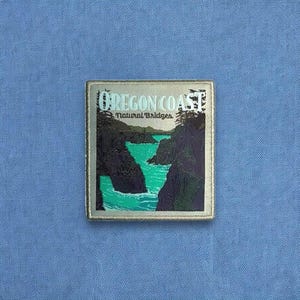 May include: A rectangular patch featuring a graphic illustration of the Oregon Coast Natural Bridges. The design displays dark rocky cliffs surrounding vibrant turquoise water, with the text Oregon Coast Natural Bridges printed in white.