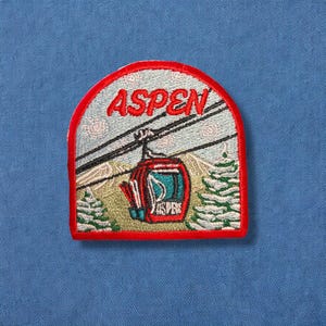 May include: Red, white, and blue embroidered patch with a cable car and the word "ASPEN" in white lettering.