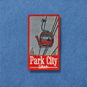 May include: Red and white embroidered patch with a cable car and the text "Park City, Utah".