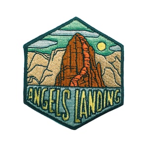 May include: Embroidered patch featuring a landscape scene with a prominent brown rock formation. The patch is in a hexagonal shape with the words "ANGELS LANDING" in a stylized font. The design includes a yellow sun, clouds, and mountains.