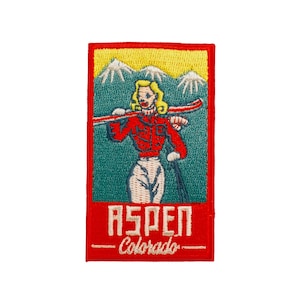 May include: Embroidered patch featuring a vintage illustration of a skier in Aspen, Colorado. The design includes a skier with skis, mountains, and the text "ASPEN - Colorado" in red and white on a rectangular patch with a red border.