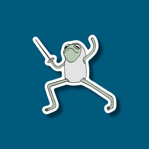 May include: A sticker featuring a cartoon frog in a fencing pose. The frog is light green with a white outfit and is holding a sword. The sticker has a white border and is set against a teal background.