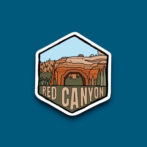 May include: A sticker with a red canyon landscape featuring a natural archway. The sticker is green and brown with the text "RED CANYON" in white.