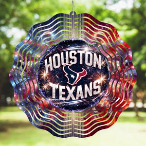 May include: A decorative wind spinner featuring the Houston Texans logo and team name. The design incorporates red, white, and blue colors with a wavy, layered pattern. The center displays the team logo and name against a starry background.