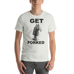 以下が含まれることがあります： 「GET FORKED」の文字と、チェスのナイトの白黒イラストがプリントされたライトグレーのTシャツ。半袖で、柔らかい素材で作られています。