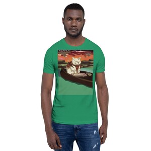 Può includere: T-shirt verde con un gatto dei cartoni animati in barca su un lago. Il gatto è bianco con una sciarpa marrone e si trova in una barca di legno. Lo sfondo mostra un tramonto con sfumature arancioni e rosse.