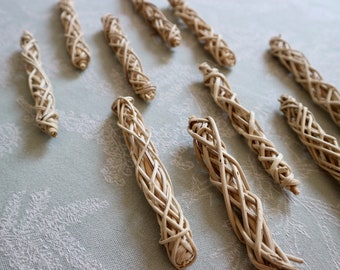 May include: A collection of ten white woven sticks, each with a unique spiral pattern. The sticks are arranged on a light blue textured surface.
