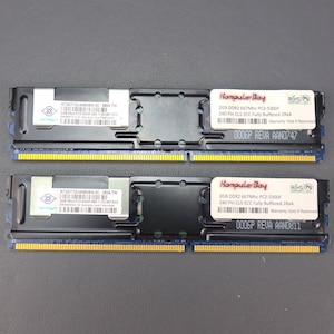 May include: Two black computer memory modules with blue and yellow accents. Each module has a sticker with the text "KomputerBay" and the text "2GB DDR2 667Mhz PC2-5300F 240 Pin CLS ECC Fully Buffered 2Rx4 Warranty Void If Removed". The top module has the text "0006P REVA AAN0747" and the bottom module has the text "0006P REVA AAN0811".