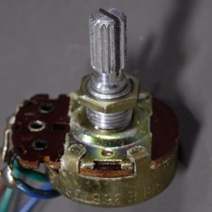 May include: A close-up of a brown and silver potentiometer with a knurled knob. The potentiometer has a label that reads "R1F 33993".