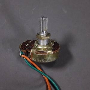 May include: A brown and gold potentiometer with a silver knob and three wires attached. The potentiometer is labeled "ERIE 389738".