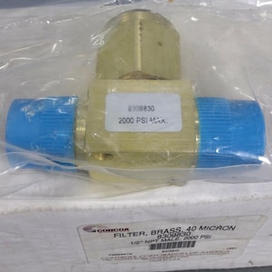 May include: A brass filter with blue caps on each end, packaged in clear plastic. The filter has a label with the text "8309830" and "2000 PSI MAX." The product is labeled as a "FILTER, BRASS, 40 MICRON."