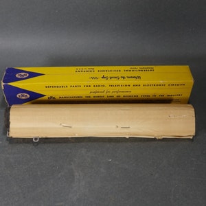 May include: A yellow and blue box with the text "LRC" and "International Resistance Company" on it. The box is labeled "Dependable Parts for Radio, Television and Electronic Circuits" and "Wherever the Circuit Says LRC".