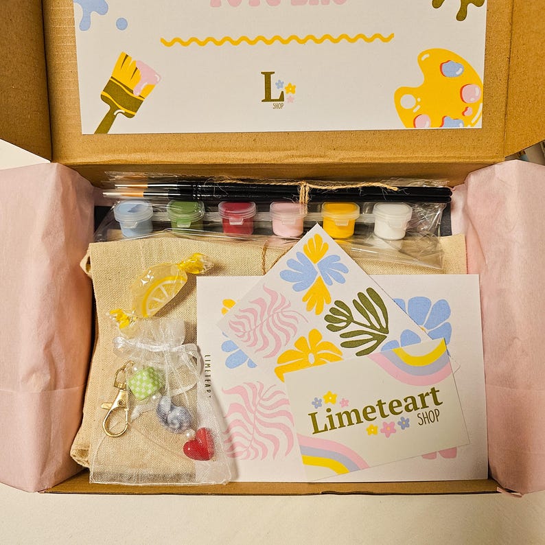 May include: An open box reveals a paint-by-numbers kit with paint pots, brushes, and a canvas. The kit includes a small bag of candies and a keychain. The box also contains cards with the text "Limeteart SHOP" and decorative floral designs.