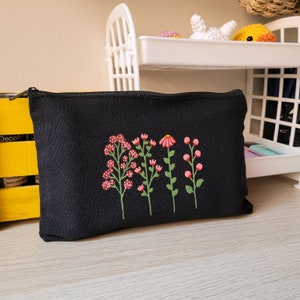 May include: Black canvas zippered pouch with embroidered pink and green flowers.
