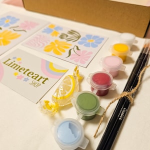 May include: A craft kit with paint pots in various colors, paintbrushes, and floral design cards. The kit includes a candy and a card with the text "Limeteart SHOP". The paint colors include white, yellow, pink, red, green, and blue.