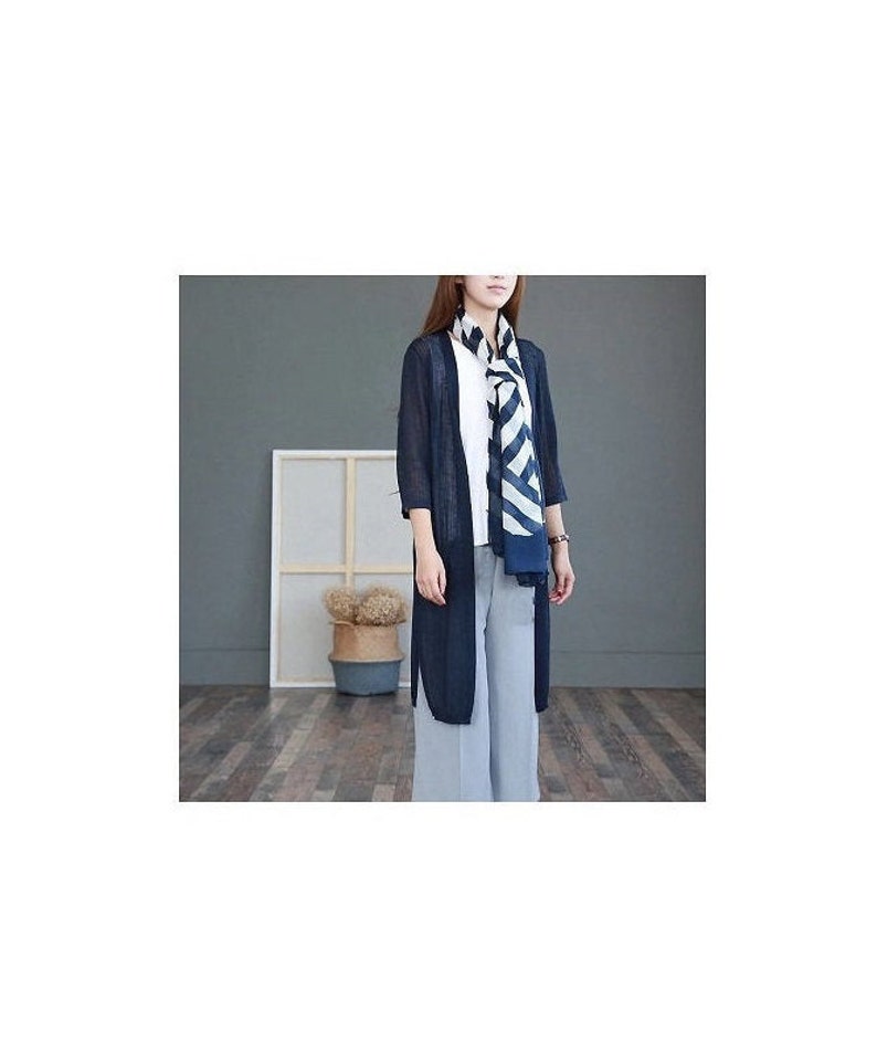 Puede incluir: Un c&aacute;rdigan largo azul marino con mangas tres cuartos, usado sobre una camiseta blanca y pantalones azul claro. Una bufanda a rayas en azul marino y blanco est&aacute; drapeada alrededor del cuello. El atuendo es casual y elegante.