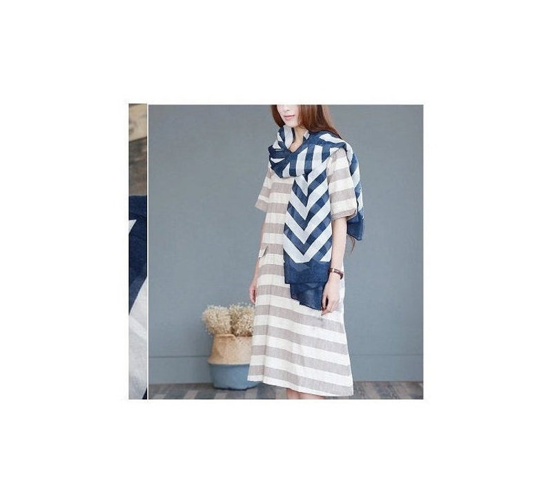 Puede incluir: Una persona con un vestido a rayas y una bufanda con estampado de chevr&oacute;n azul y blanco. El vestido tiene rayas horizontales en tonos neutros. La bufanda est&aacute; drapeada alrededor del cuello y los hombros.