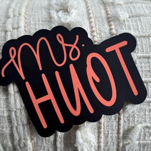 Puede incluir: Un letrero en blanco y negro con el texto "Mrs. Hiott" en rosa.