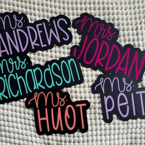 Puede incluir: Cinco etiquetas de nombre de profesor en blanco y negro con letras de colores. Los nombres son "Mrs. Andrews", "Mrs. Richardson", "Mrs. Jordan", "Mrs. Huot" y "Mrs. Peitz".