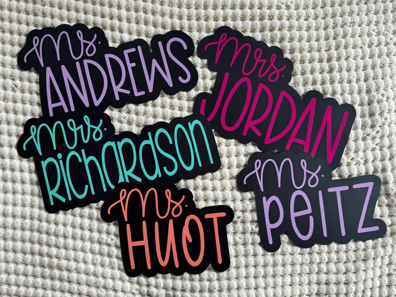 Puede incluir: Cinco etiquetas de nombre de profesor en blanco y negro con letras de colores. Los nombres son "Mrs. Andrews", "Mrs. Richardson", "Mrs. Jordan", "Mrs. Huot" y "Mrs. Peitz".