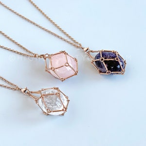 May include: Three gold necklaces with geometric wire cages holding clear quartz, rose quartz, and amethyst crystals. Choose your crystal - Clear Quartz, Rose Quartz, Amethyst -