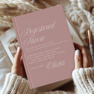 May include: A dusty rose hardcover book with white text that reads Registered Nurse (rej-uh-sterd ners) noun, Someone who shows up with both expertise and heart - resilient, caring, and trusted when it matters most. SEE ALSO: Olivia.