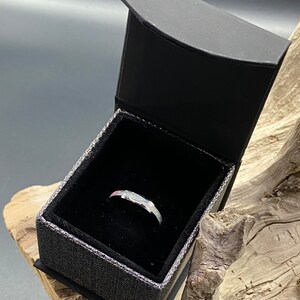 May include: A silver ring with a white opal stone set in a black ring box.