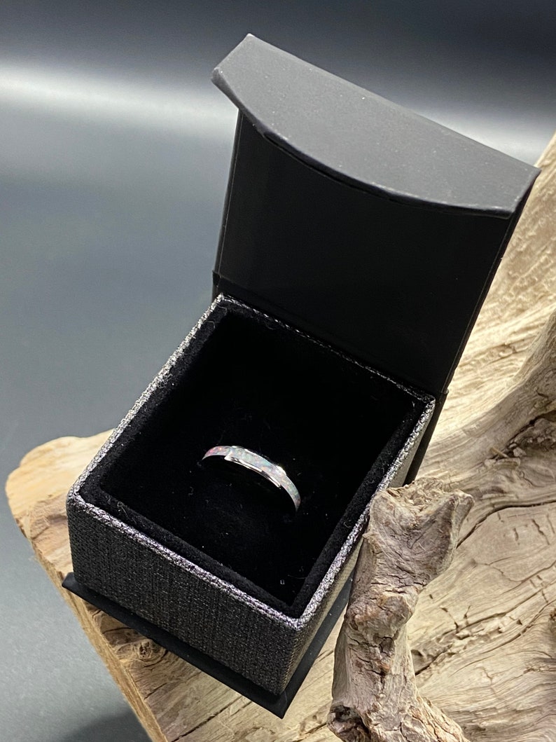 May include: A silver ring with a white opal stone set in a black ring box.