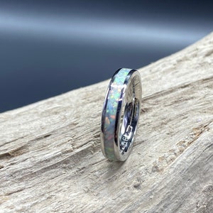 May include: A silver ring with a thin band of white opal inlay.