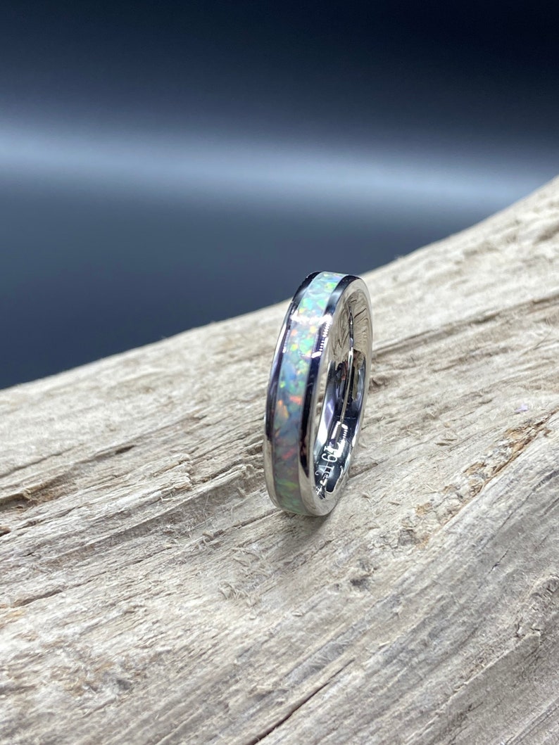 May include: A silver ring with a thin band of white opal inlay.