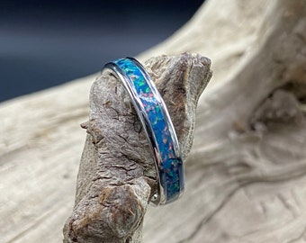 May include: A silver band ring with a blue and white opal inlay.