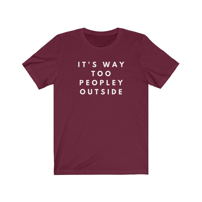 May include: Burgundy short-sleeved t-shirt with white text that reads "It's Way Too Peopley Outside".