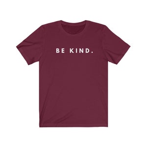 Puede incluir: Una camiseta color burdeos con el texto "BE KIND." impreso en blanco en la parte delantera.