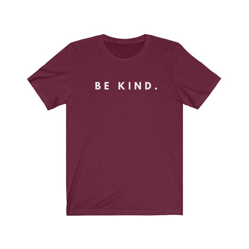 Puede incluir: Una camiseta color burdeos con el texto "BE KIND." impreso en blanco en la parte delantera.