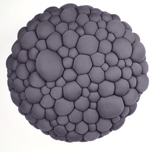 May include: A spherical, gray decorative object with a textured surface composed of numerous, irregularly shaped, rounded protrusions. The object is set against a plain white background, emphasizing its unique, organic form.