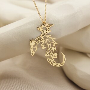 May include: Gold necklace with a geometric dragon pendant. The dragon is made of a delicate, openwork design.