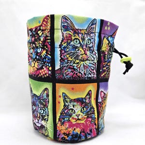 May include: A colorful drawstring bag with a patchwork design featuring multiple images of cats. The bag is made of fabric and has a black drawstring.