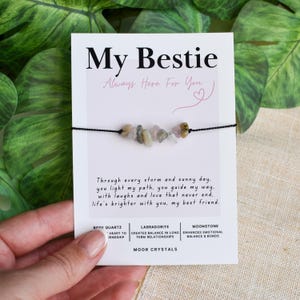 May include: A black string bracelet with a row of colorful gemstones, displayed on a white card. The card reads "My Bestie" with the text "Always Here For You" and a poem. The card also lists the gemstones as Rose Quartz, Labradorite, and Moonstone.