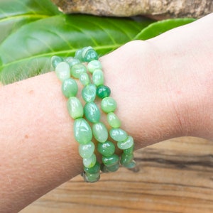 Op de afbeelding: Een drievoudige armband gemaakt van lichtgroene jade kralen. De kralen zijn glad en gepolijst en geregen aan een doorzichtig elastisch koord.