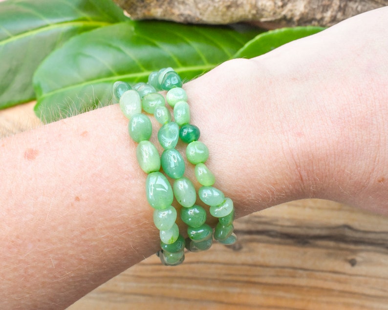 Op de afbeelding: Een drievoudige armband gemaakt van lichtgroene jade kralen. De kralen zijn glad en gepolijst en geregen aan een doorzichtig elastisch koord.