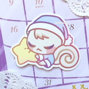 May include: A sticker of a cartoon animal wearing a blue and white sleep cap, holding a yellow star and curled up with a brown tail. The sticker is on a purple and white calendar with the text "HAI YUN MOE" and the number "18" visible.