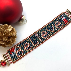 May include: A beaded bracelet with the word "Believe" in white beads on a dark blue background. The bracelet has red and gold beads and a red and white candy cane design. The bracelet has gold metal clasps with a bell charm.