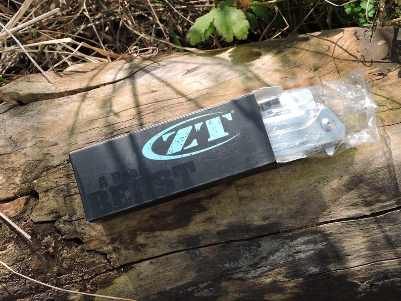 May include: A white ceramic mug with a black handle and the text "But First, Coffee" in a bold, black font. The mug is filled with a dark liquid, likely coffee, and sits on a light-colored surface.