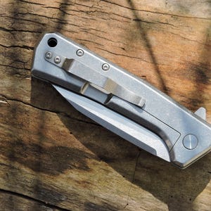 May include: A set of three ceramic mugs with a speckled, matte finish. The mugs are in shades of cream, light gray, and dark gray. Each mug has a simple, modern design and a rounded handle.