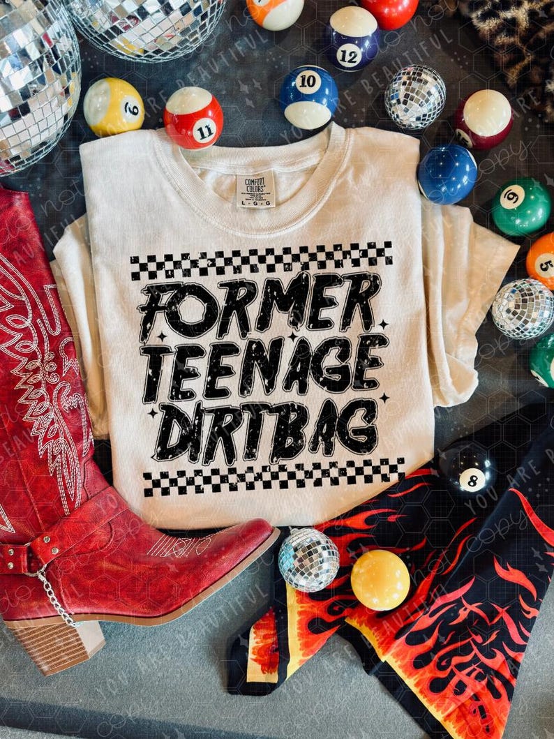 K&ouml;nnte beinhalten: Cremefarbenes T-Shirt mit dem schwarzen Text "FORMER TEENAGE DIRT BAG" und einem Schachbrettmuster. Umgeben von roten Cowboy-Stiefeln, Discokugeln und Billardkugeln.
