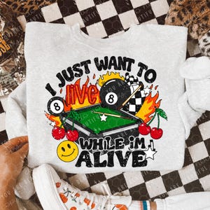 May include: Gray sweatshirt with a graphic print of a pool table, cherries, and flames. The text reads "I just want to live while I'm alive".