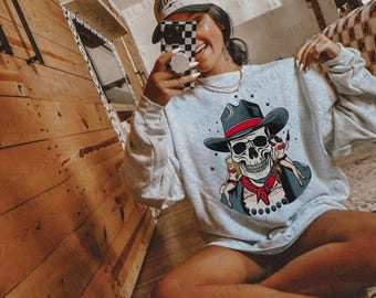 May include: A light gray sweatshirt with a graphic print of a skull wearing a cowboy hat and holding two women. The text "You are beautiful" is printed on the sweatshirt.